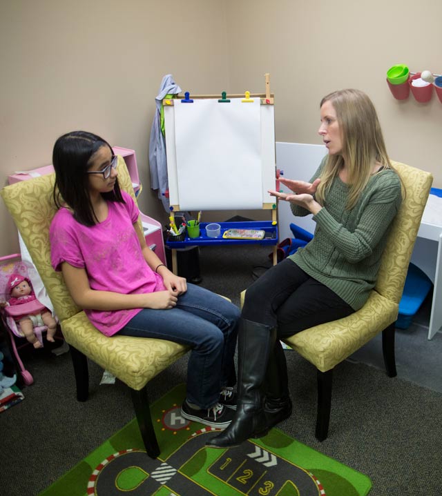 Therapist uses sign language to communicate with deaf child.